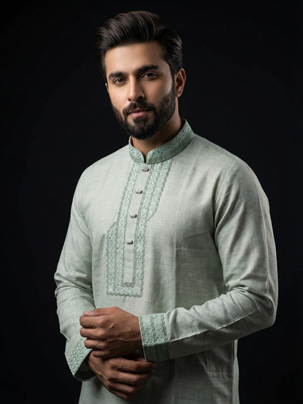 Man wearing a light green kurta with intricate patterns on a black background